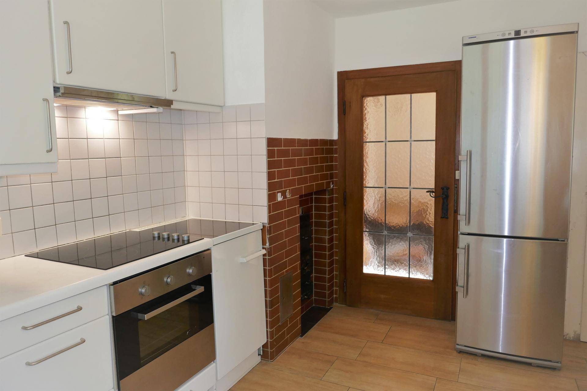 Funktionale Küche mit weißen Schränken, Kochfeld und Kühlschrank, bereit zur Nutzung.