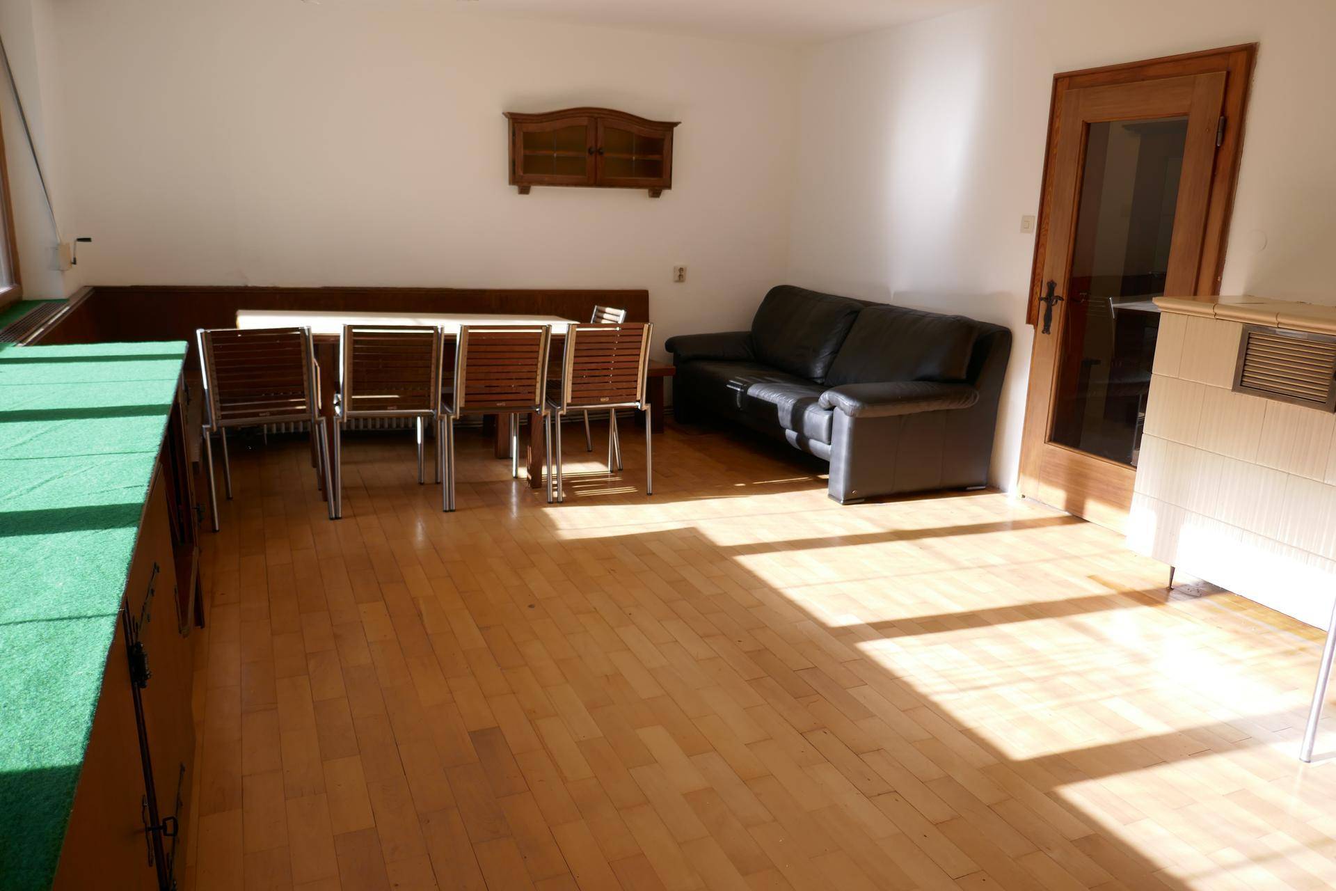 Heller Wohn- und Essbereich mit Sofa und Kachelofen, ideal für gesellige Stunden.