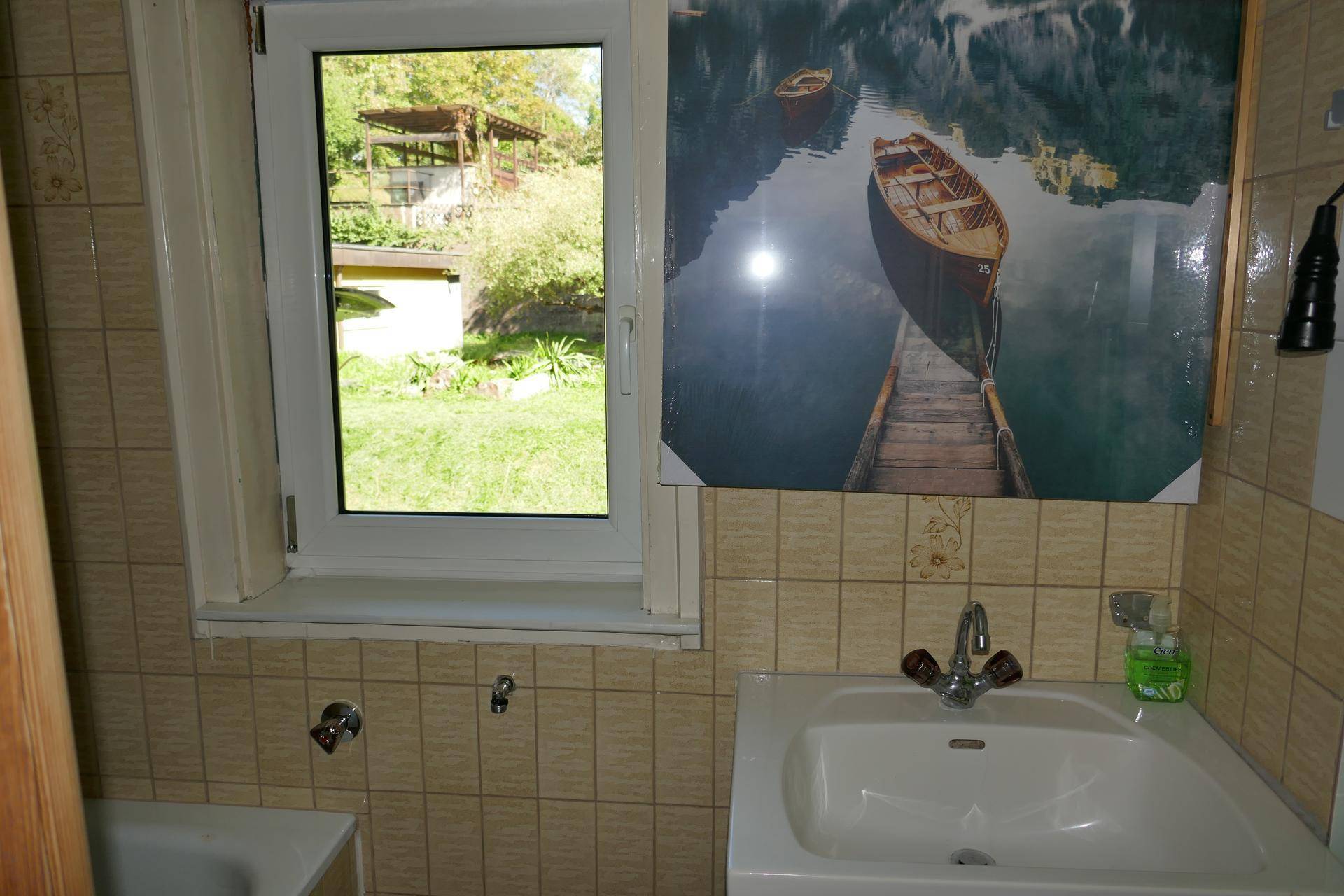 Traditionelles Badezimmer mit Waschbecken, Fenster und gefliesten Wänden.