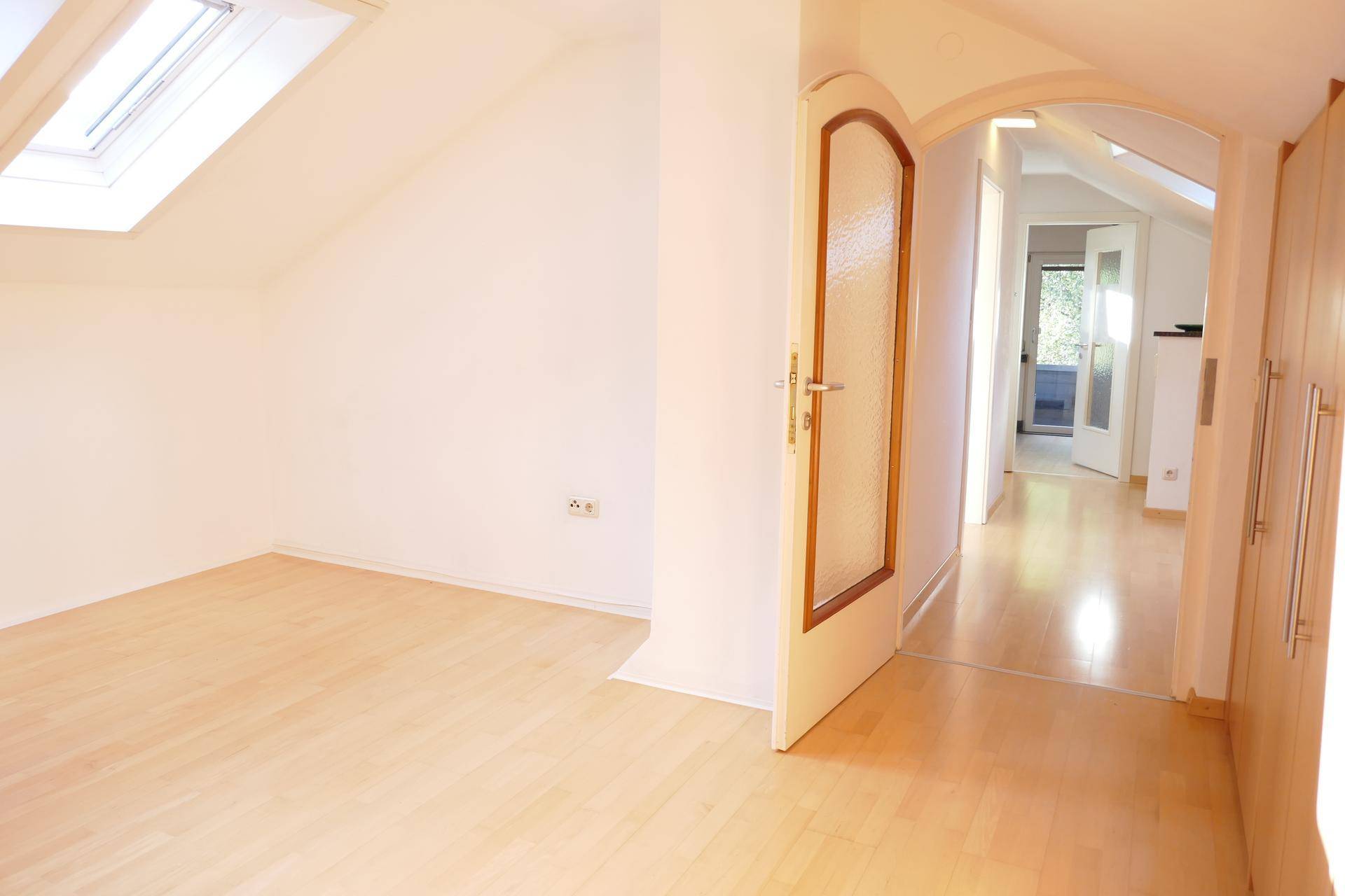 Helles Zimmer im Dachgeschoss mit Dachfenster und hellem Holzboden.