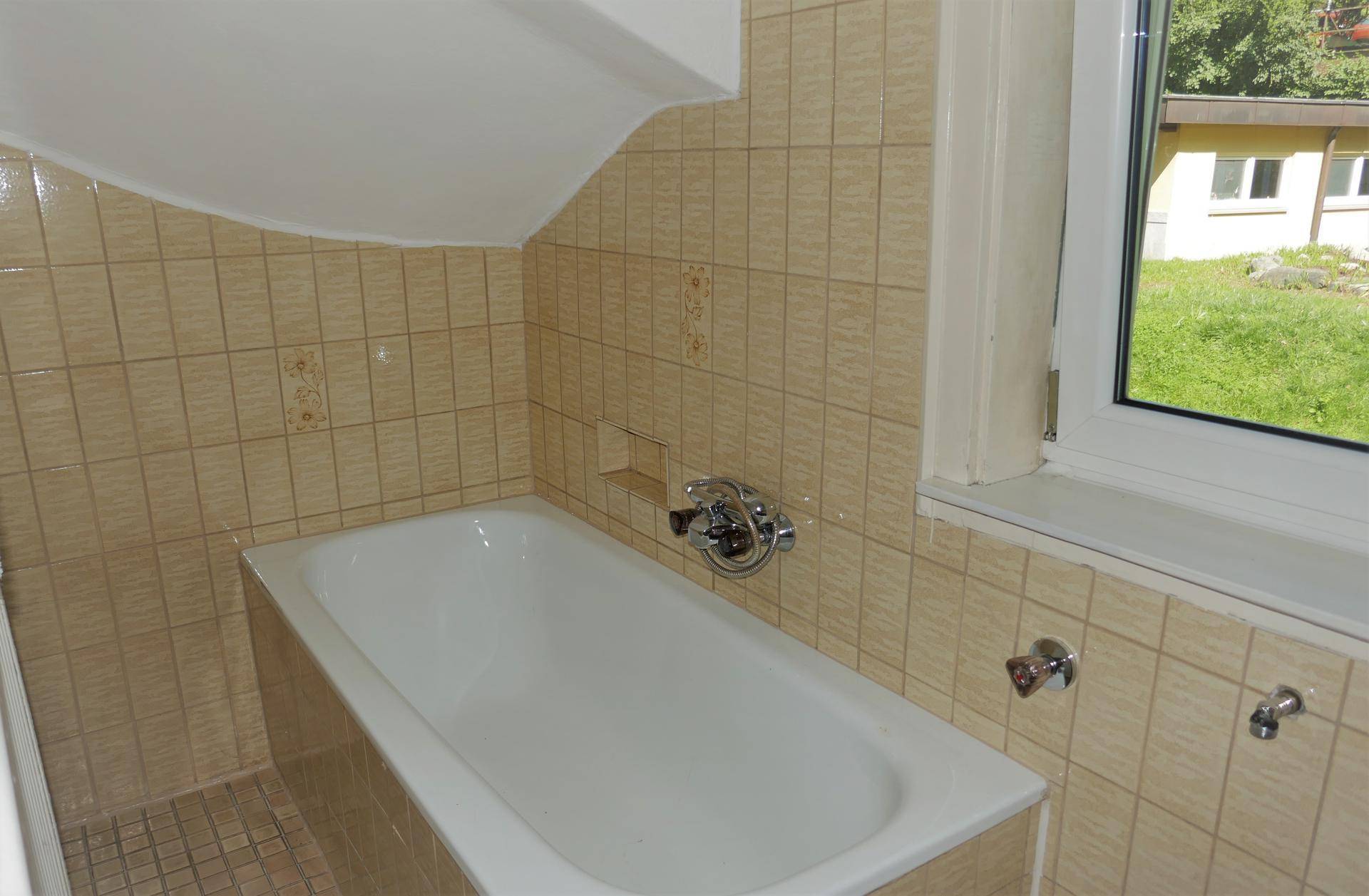 Klassisches Badezimmer mit Badewanne und gefliesten Wänden, hell und funktional.
