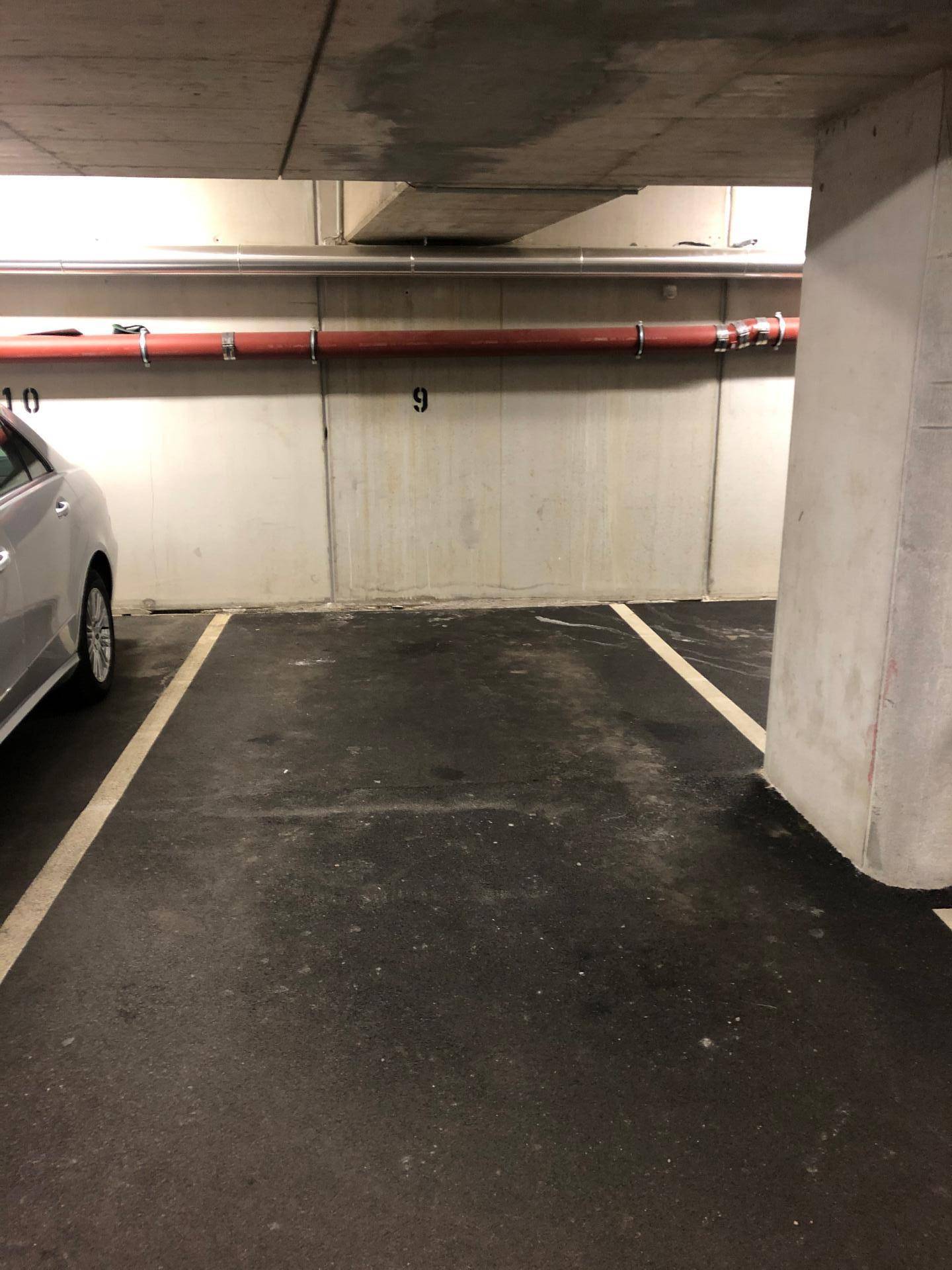 Innenansicht einer Tiefgarage mit markierten Stellplätzen und einem geparkten Fahrzeug.
