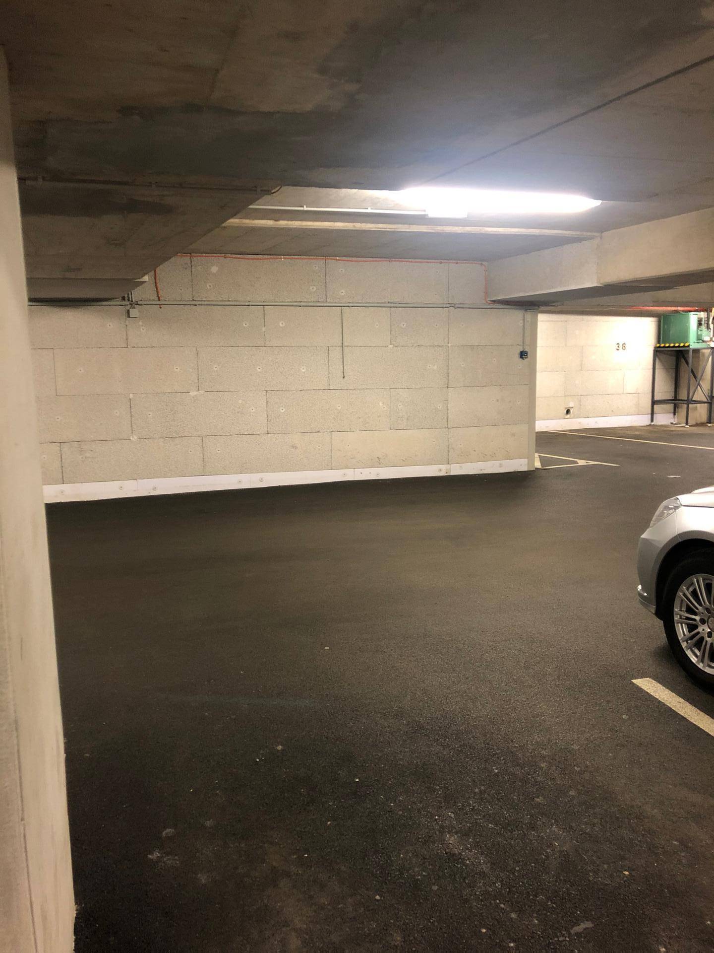 Geräumige Tiefgarage mit hellen Wänden, Betonpfeilern und ausreichend Parkflächen.