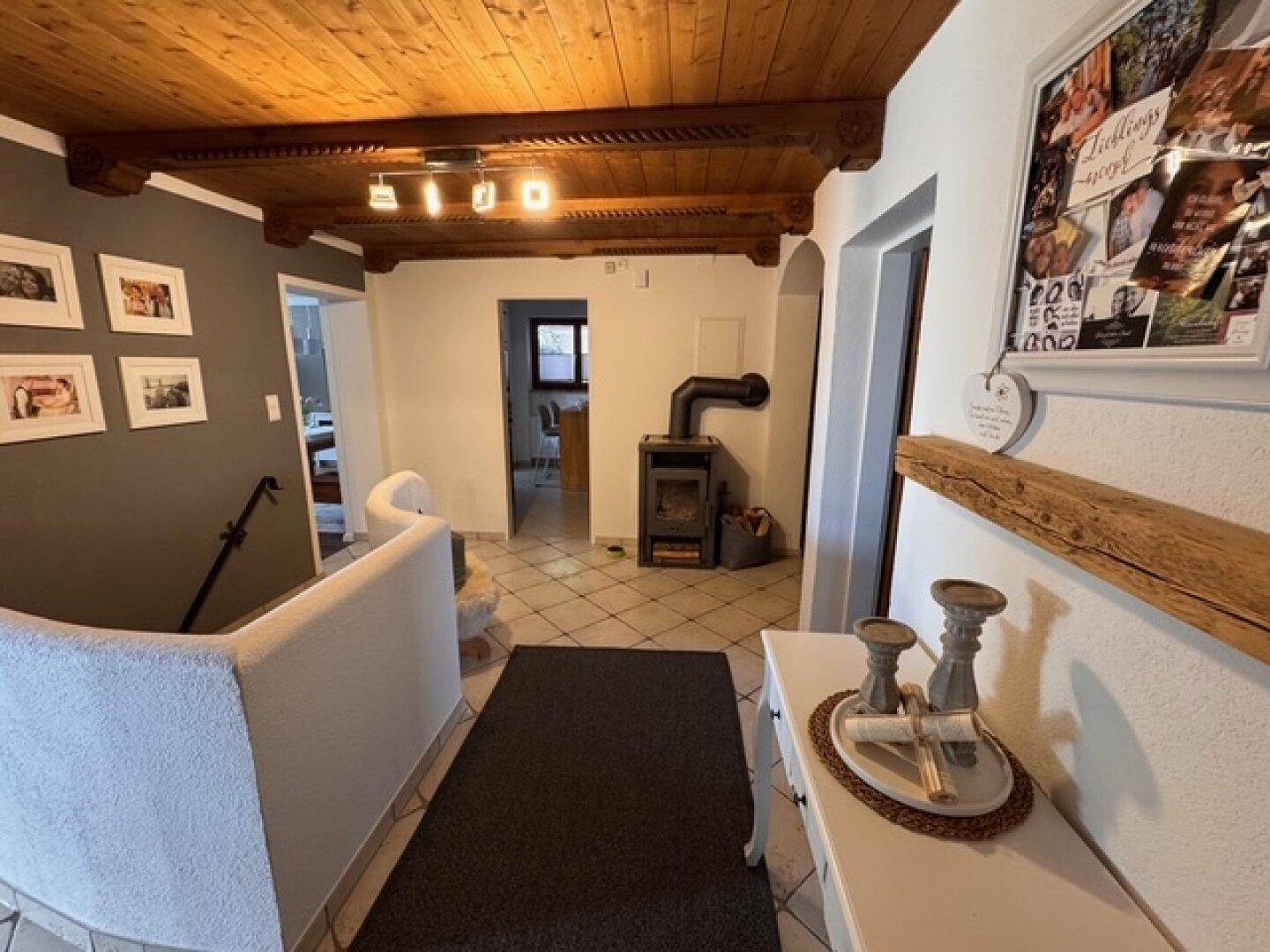 Flur mit rustikaler Holzdecke, Kaminofen und Treppenaufgang in traditionellem Stil.