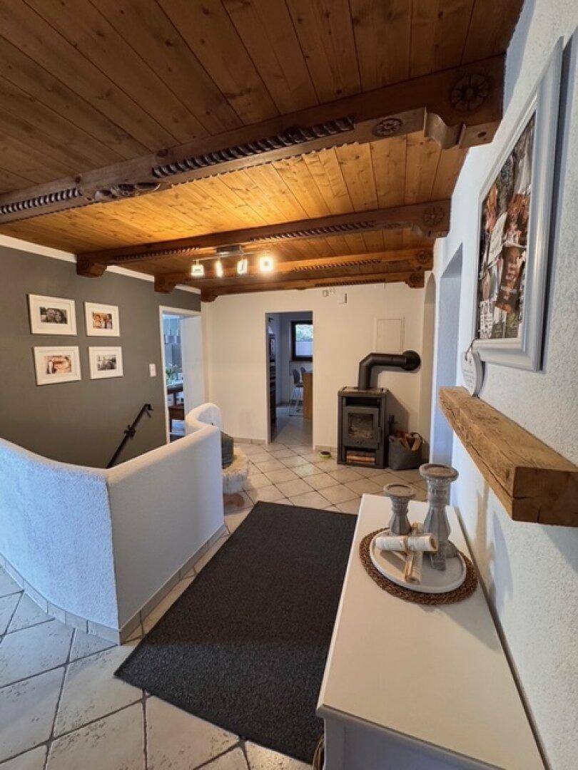 Eingangsbereich mit traditioneller Holzdecke, Kaminofen und gefliestem Boden.