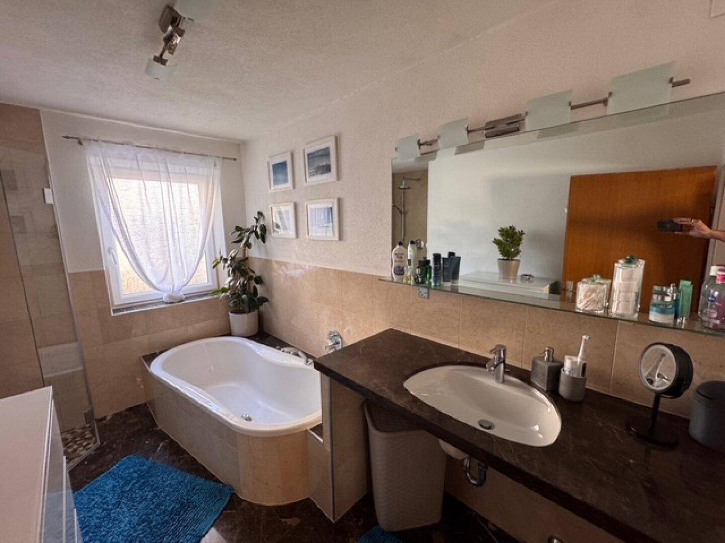 Geräumiges Badezimmer mit Badewanne, großem Spiegel und modernem Waschtisch.