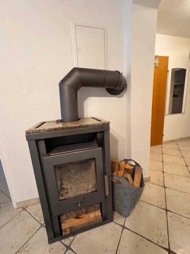 Detailansicht eines modernen Kaminofens mit Holzscheiten im Flurbereich.