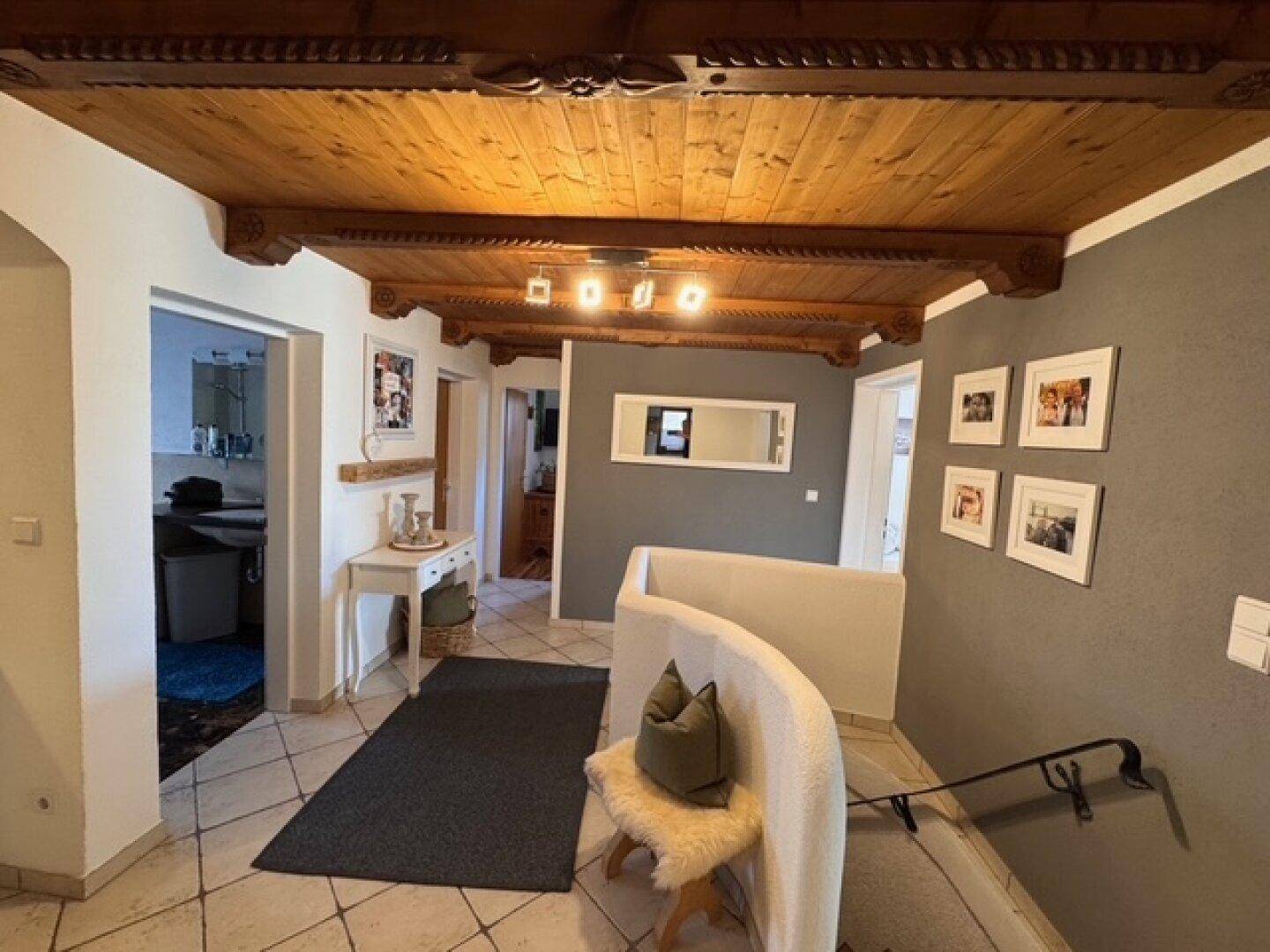 Geräumiger Flur mit rustikaler Holzdecke, gefliestem Boden und Treppenaufgang.