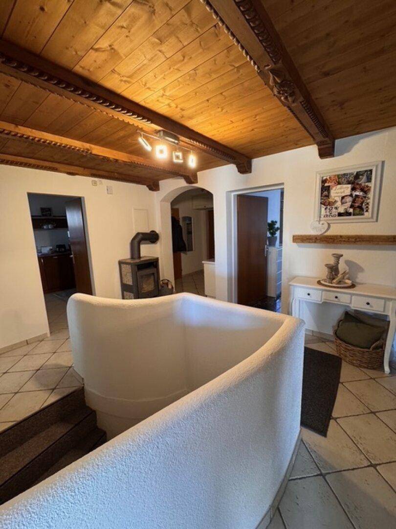 Heller Flur mit traditioneller Holzdecke, geschwungener Treppe und Fliesenboden.