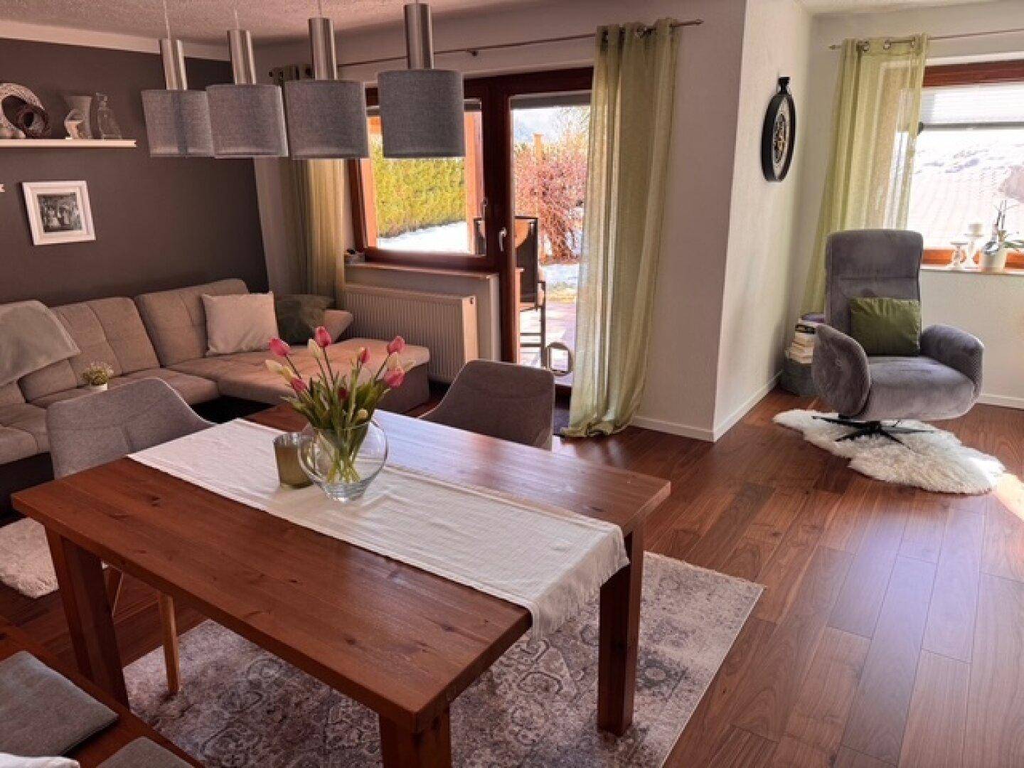 Heller Wohn-Essbereich mit Holzboden, Esstisch und Blick ins Grüne.