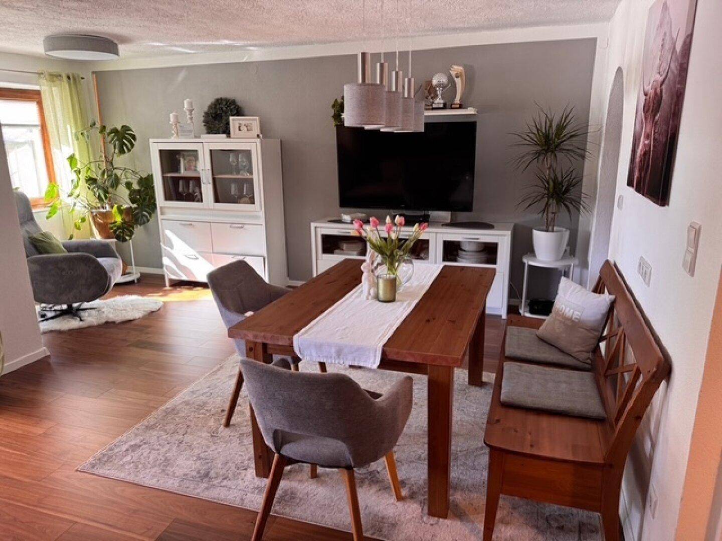 Offener Wohn-Essbereich mit Holzboden, Esstisch und gemütlicher Sitzecke.