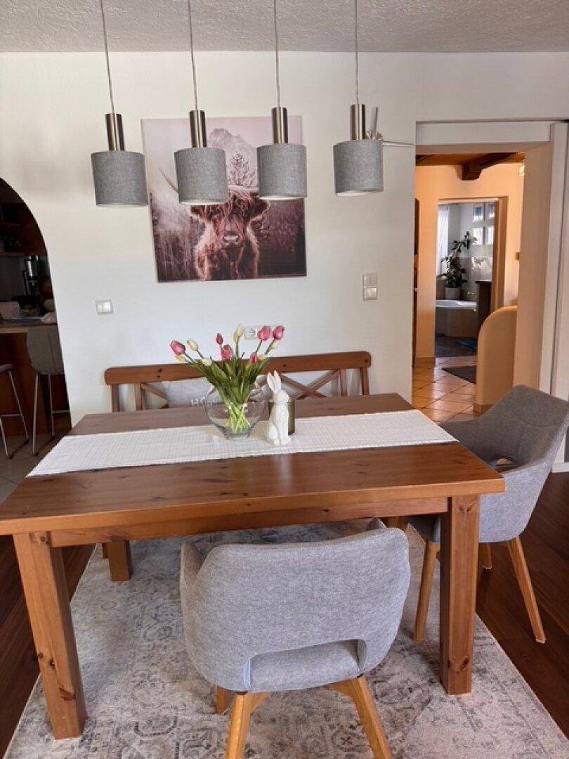 Essbereich mit rustikalem Holztisch, bequemen Stühlen und moderner Pendelleuchte.