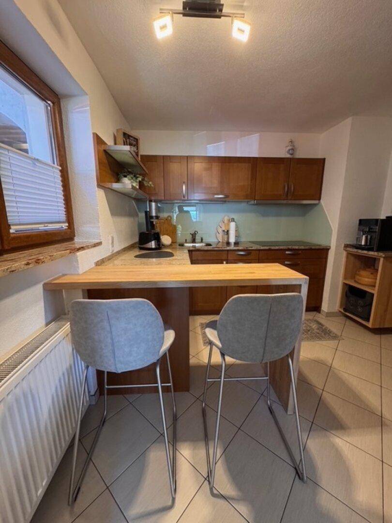 Küche mit Frühstücksbar, zwei Barhockern und Blick aus dem Fenster.