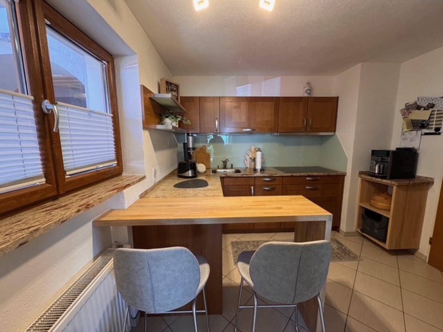 Funktionale Küche mit Holzfronten, Granitarbeitsplatte und integrierter Frühstückstheke.