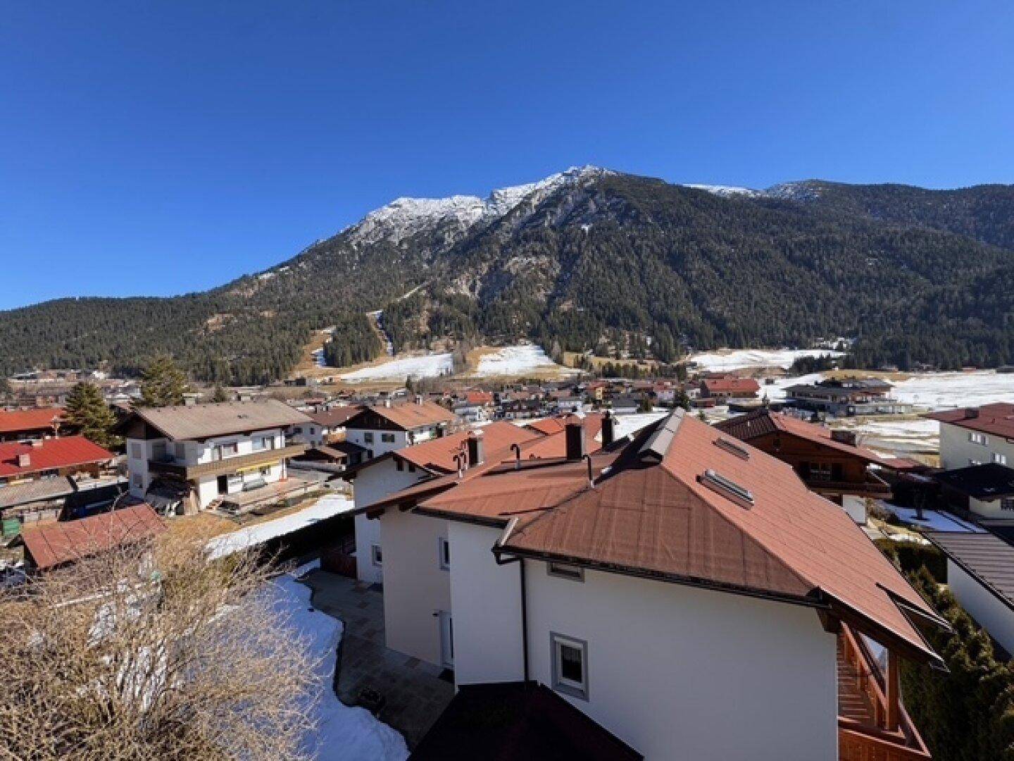Weitblick über eine Siedlung in den Bergen mit traditionellen Häusern und verschneiter Landschaft.