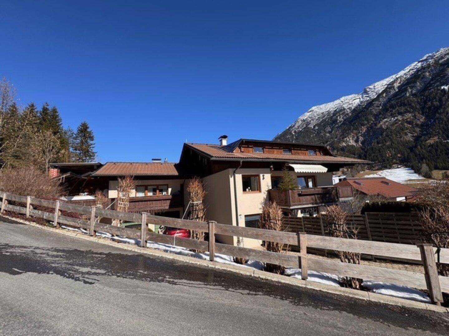 Wohnhaus in den Alpen mit traditioneller Architektur, umgeben von Natur und Bergen.