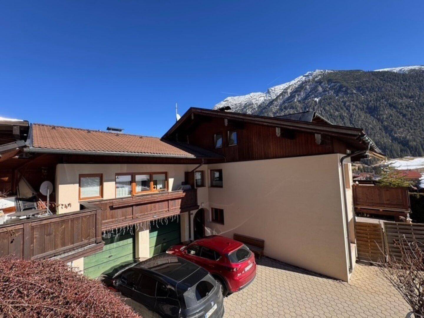 Alpines Wohnhaus mit gepflasterter Auffahrt und beeindruckendem Bergblick im Winter.