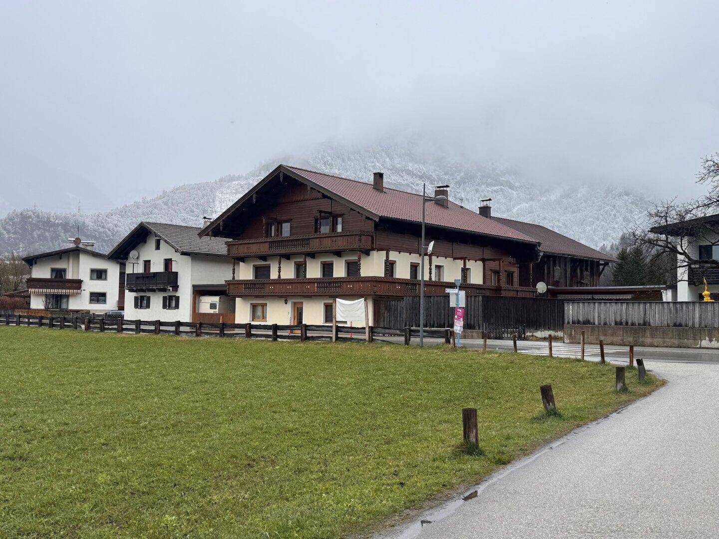 Traditionelles Wohnhaus mit Holzbalkonen und Satteldach in einer bergigen Landschaft.