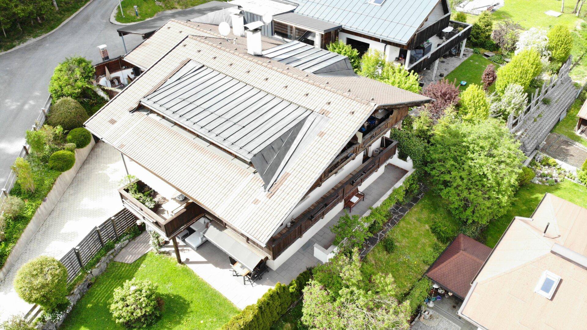 Dachansicht des Hauses mit Solarpaneelen, Balkonen und einem gepflegten Gartenbereich.
