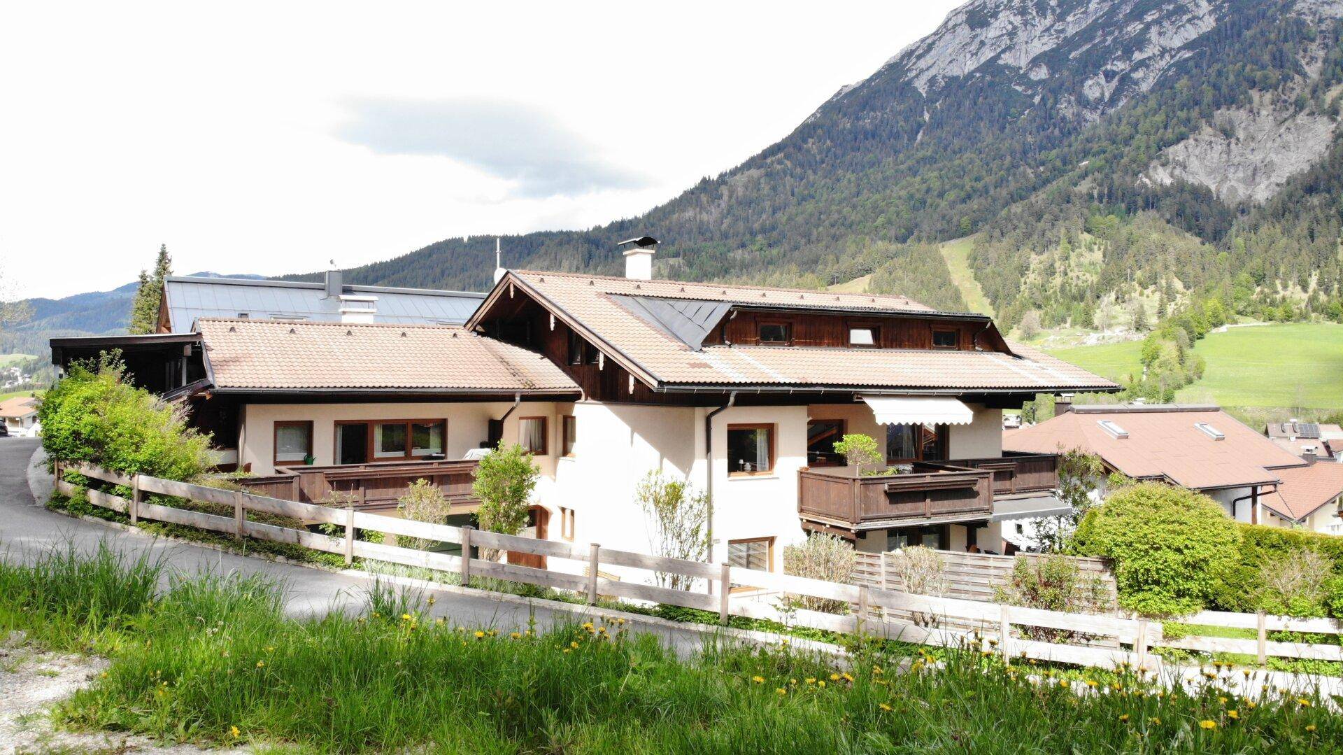 Charmantes Wohnhaus mit traditioneller Architektur und Balkonen vor beeindruckender Bergkulisse.