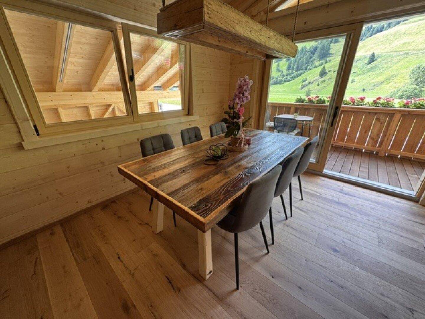 Rustikaler Essbereich mit großem Holztisch und Zugang zum Balkon mit Bergblick.