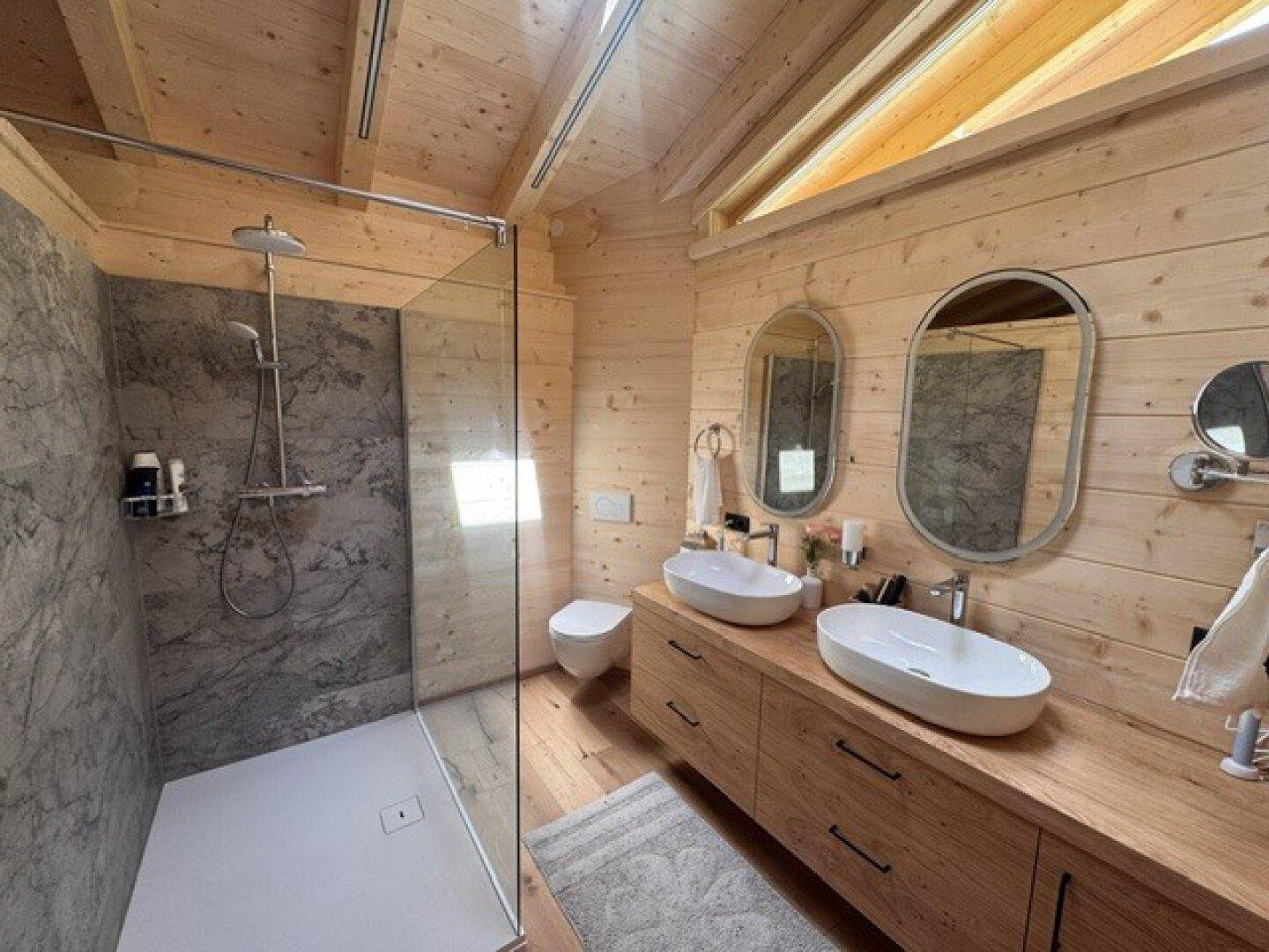 Modernes Badezimmer mit begehbarer Dusche, Doppelwaschbecken und Holzdetails.