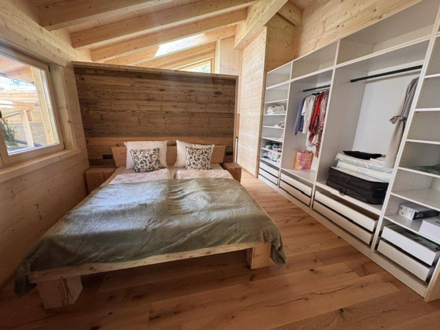 Gemütliches Schlafzimmer mit Holzwänden, Einbauschränken und viel Tageslicht.