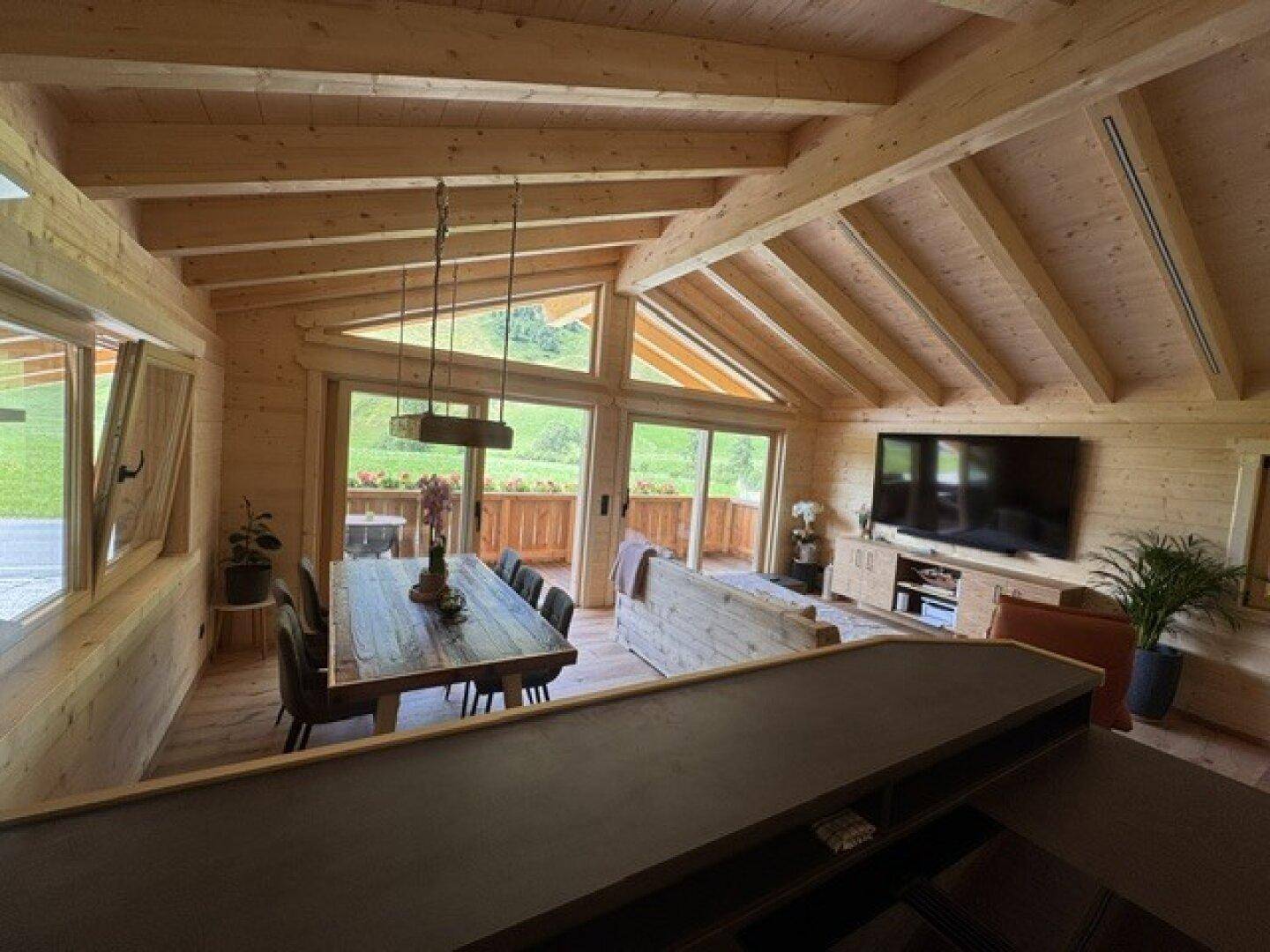 Geräumiger Wohn- und Essbereich mit Holzbalken und Panoramablick auf die Berge.