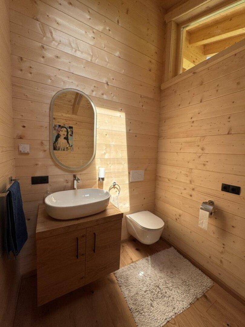 Helles Schlafzimmer mit Holzwänden, modernem Waschbecken, wandhängendem WC und Fenster.