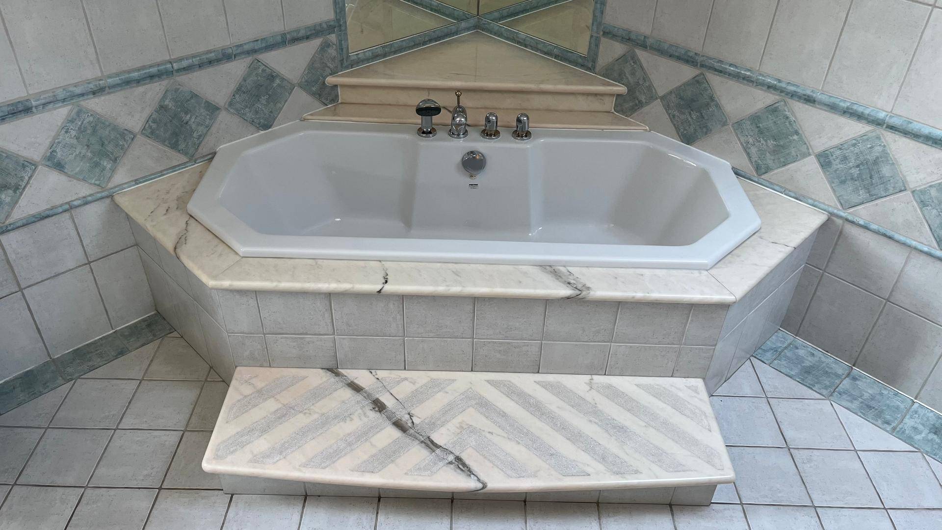 Detailansicht der Eckbadewanne mit Marmorverkleidung und passenden Stufen.