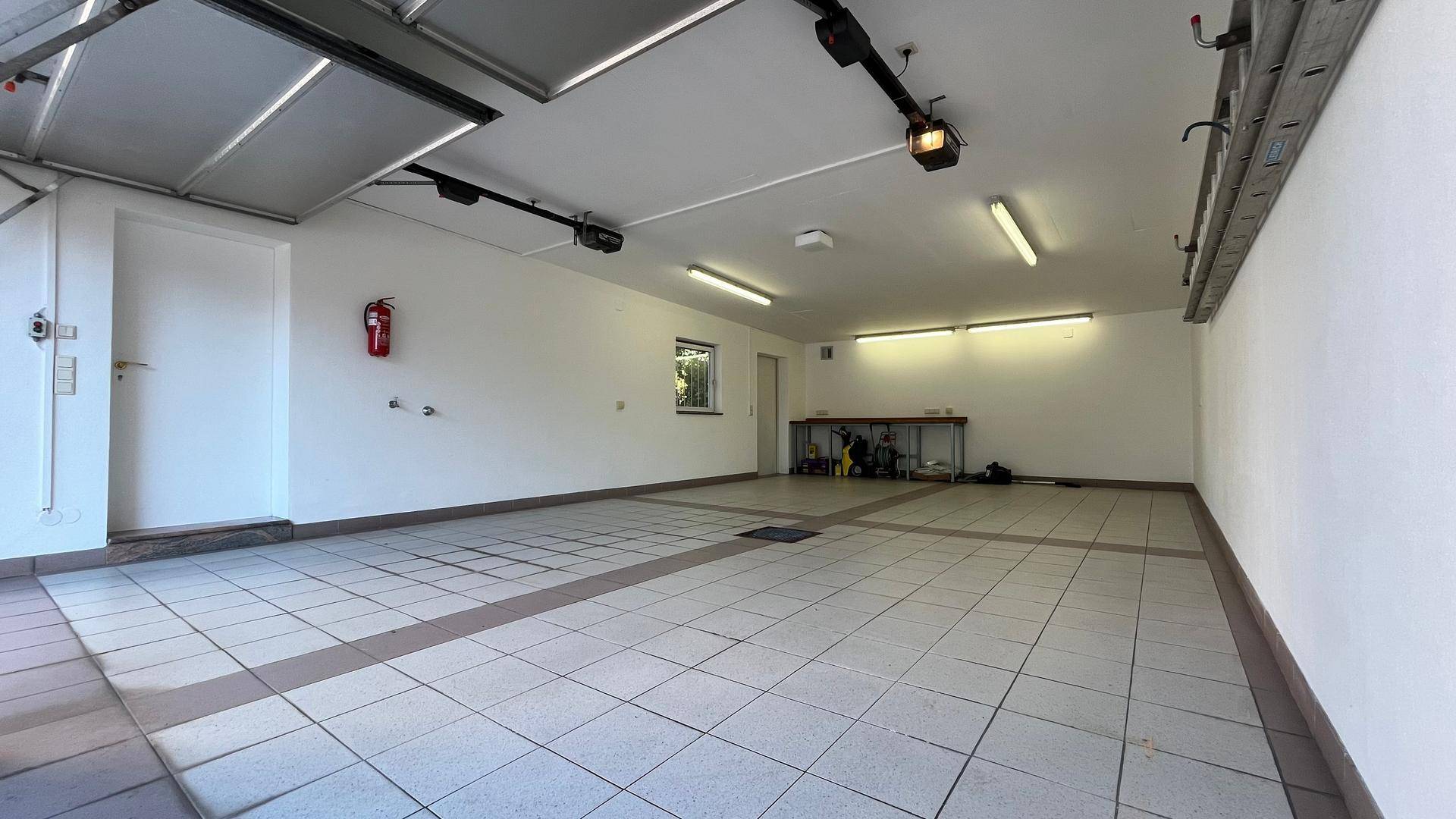 Geräumige Doppelgarage mit gefliestem Boden, Fenstern und ausreichend Platz.