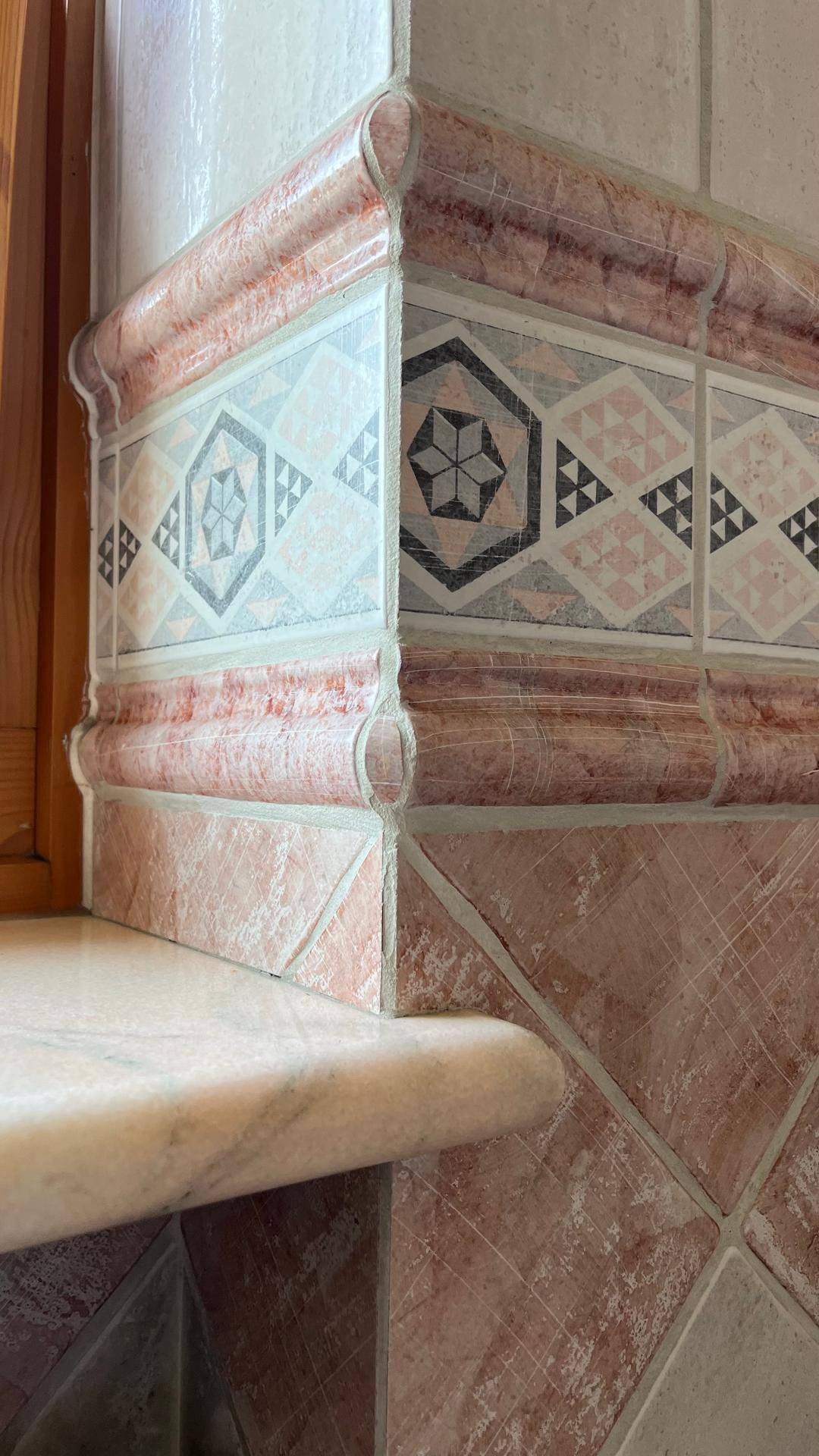 Detailaufnahme von dekorativen Fliesen mit geometrischen Mustern und Marmorakzenten.
