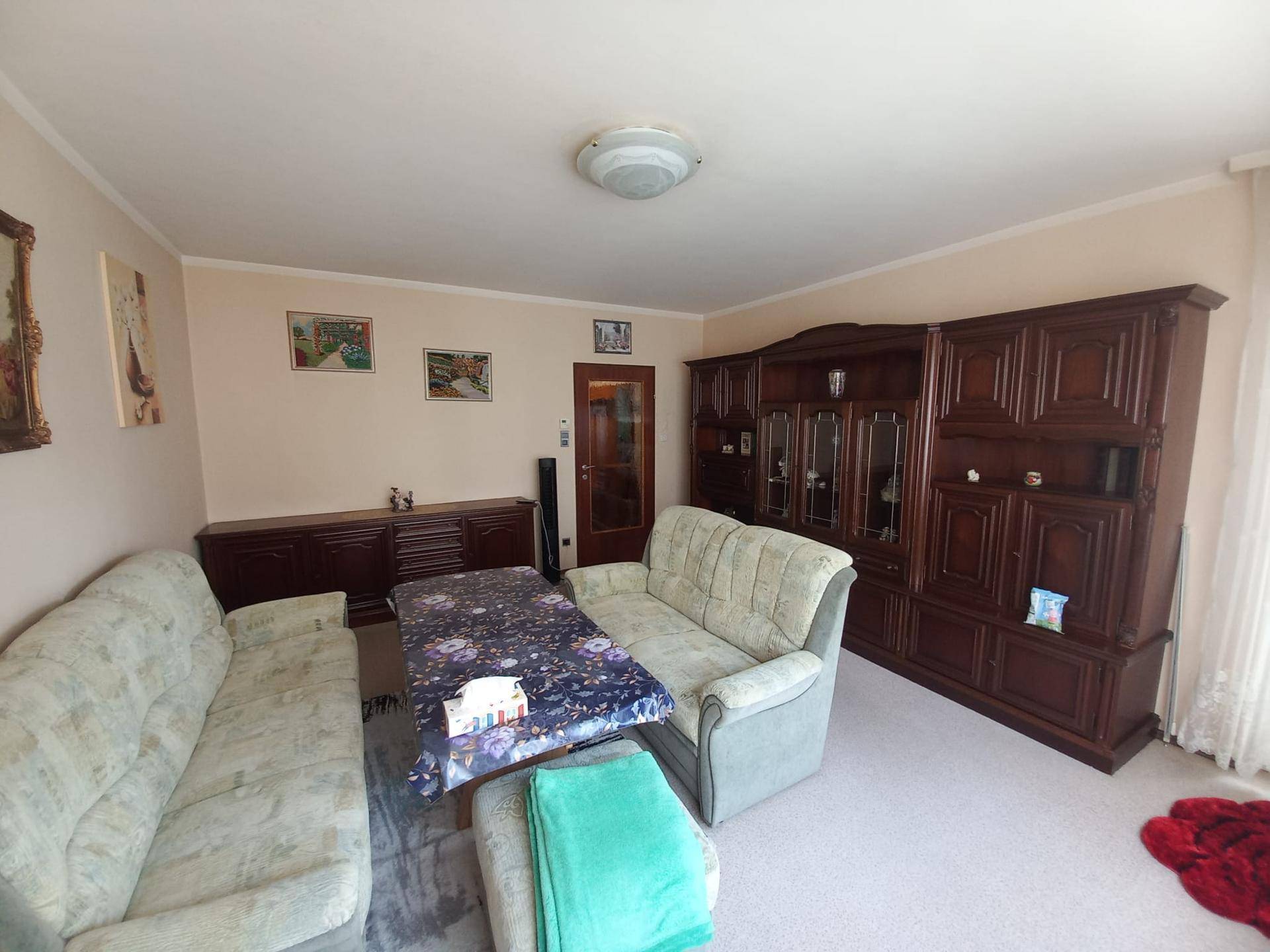 Geräumiges Wohnzimmer mit traditionellen Holzmöbeln, bequemen Sofas und einem großen Schrank.