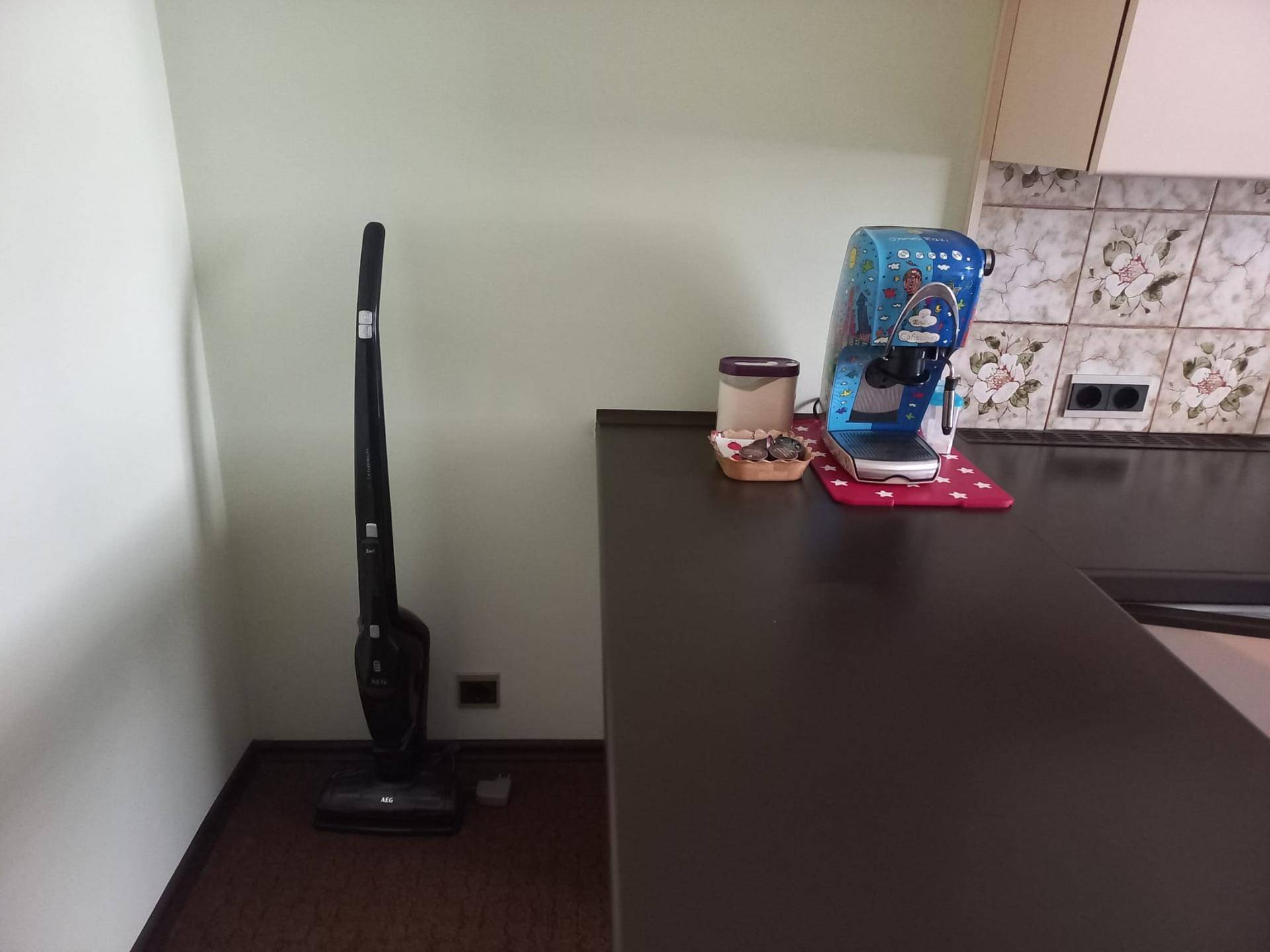 Küchenecke mit einer Kaffeemaschine auf der Arbeitsplatte und einem praktischen Staubsauger.