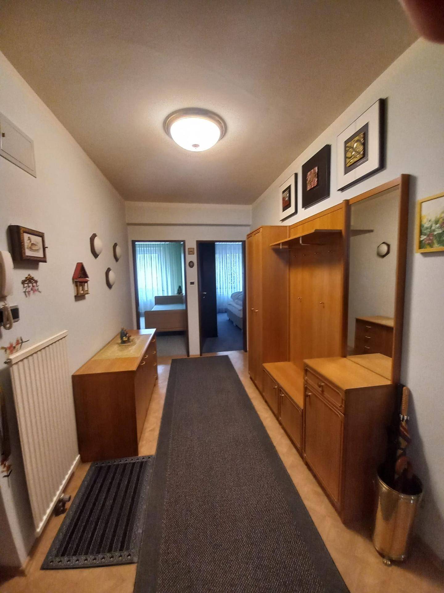 Geräumiger Flur mit Holzgarderobe, Spiegel und einem langen Teppichläufer, der den Eingangsbereich schmückt.