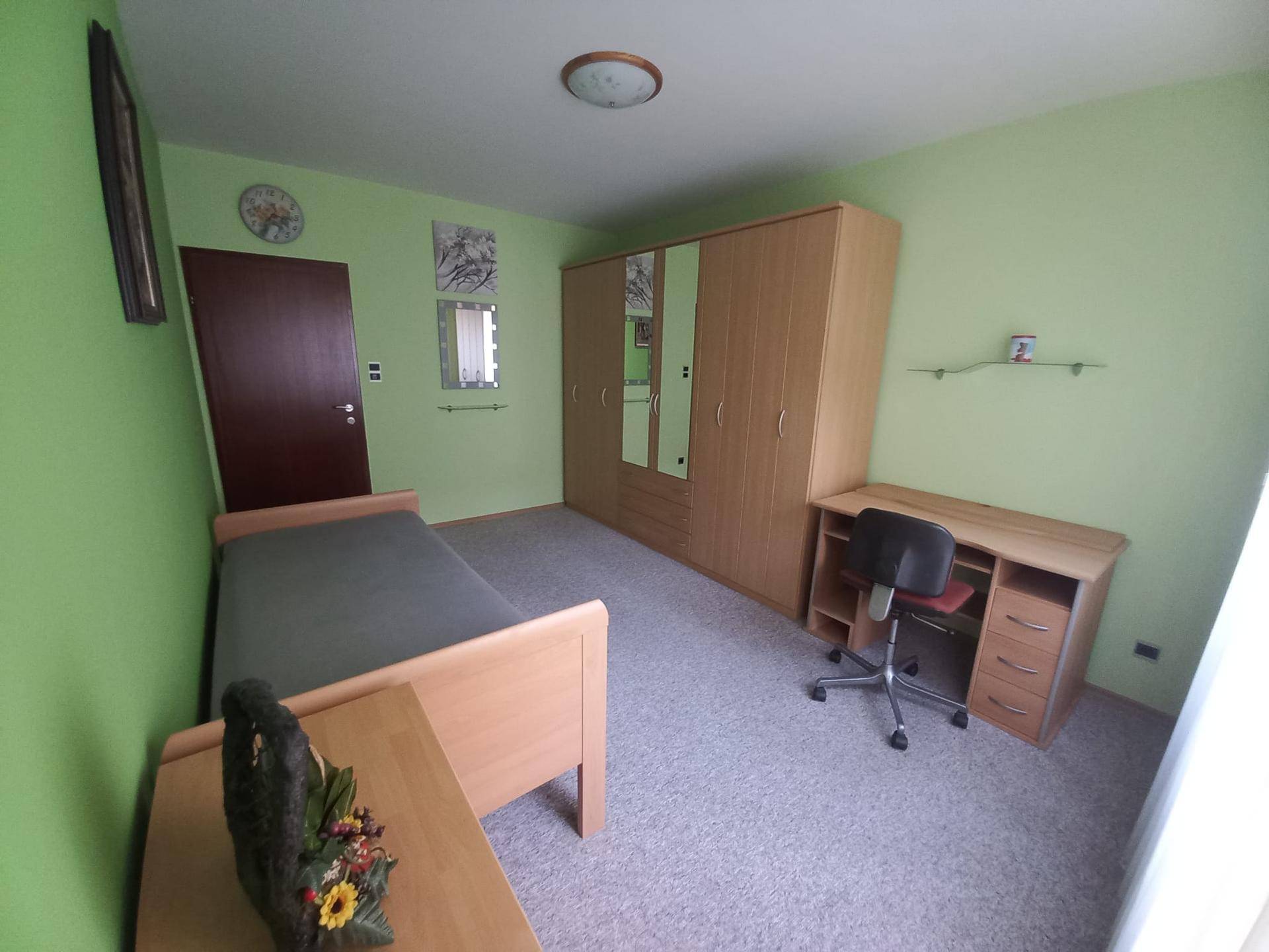 Schlafzimmer mit grünen Wänden, einem Kleiderschrank mit Spiegeltüren und einem funktionalen Schreibtisch.