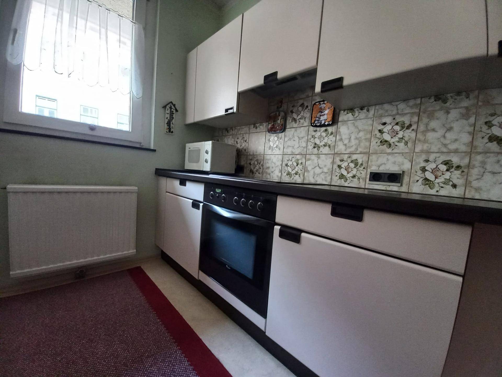 Küchenzeile mit integriertem Backofen, dunkler Arbeitsplatte und dekorativen Fliesen als Spritzschutz.