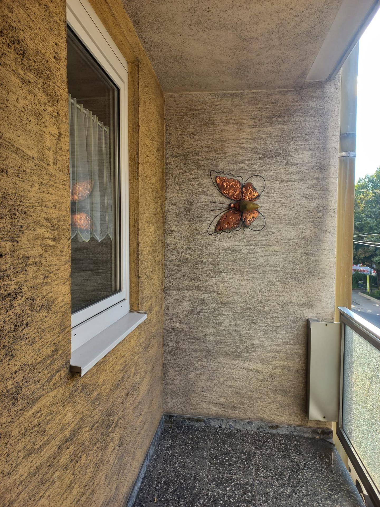 Kleiner Balkon mit strukturierter Wand und einem Metallgeländer, ideal für frische Luft.