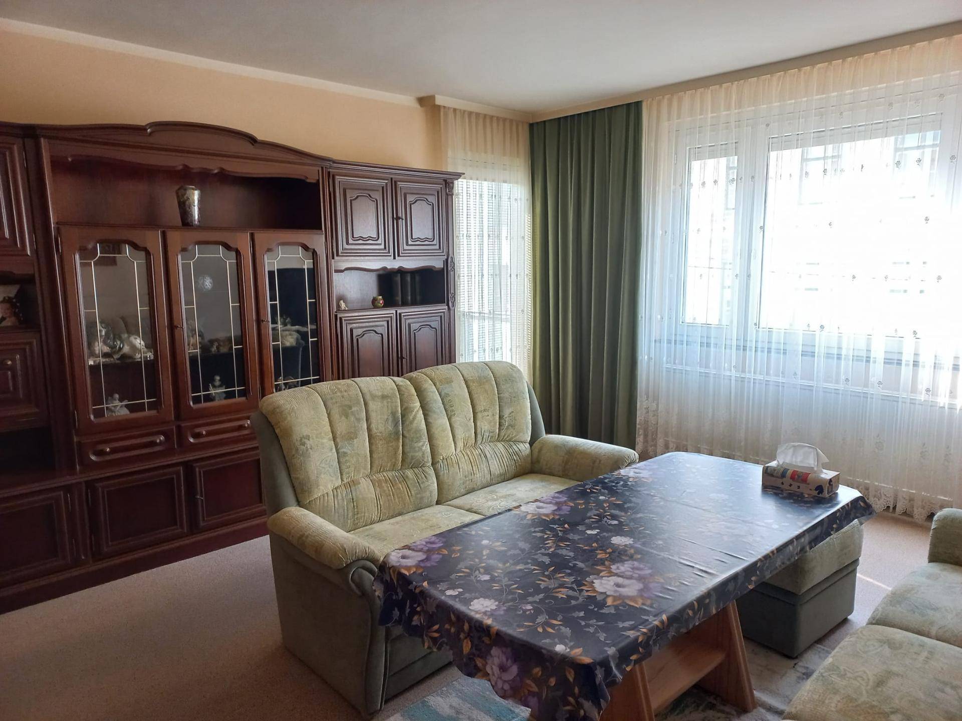 Helles Wohnzimmer mit einem großen Fenster, das viel Sonnenlicht hereinlässt, und einem gemütlichen Sofa.