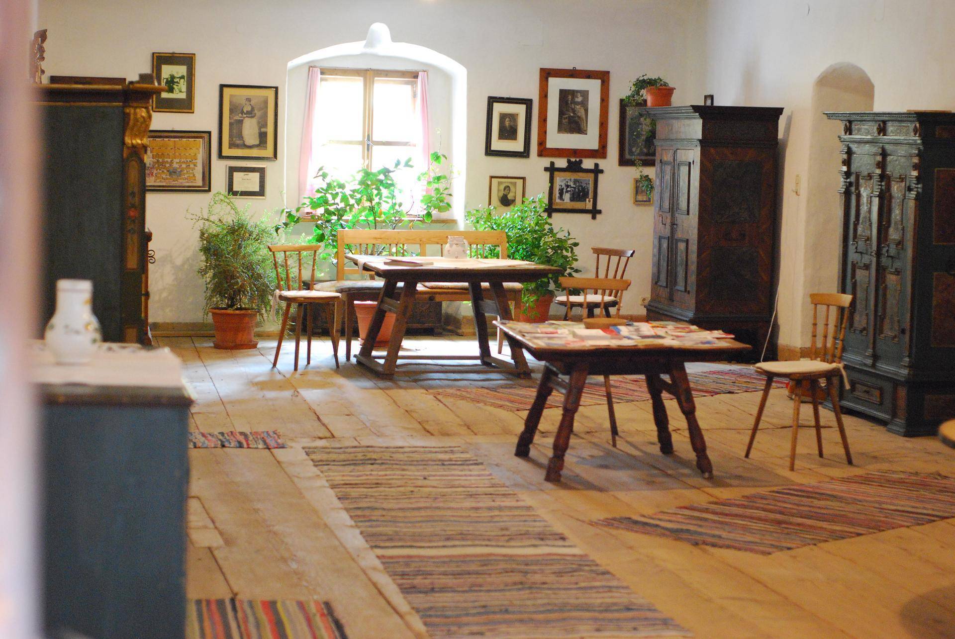 Geräumiger Wohn- und Essbereich mit Holzdielenboden, traditionellen Möbeln und vielen gerahmten Bildern an den Wänden.