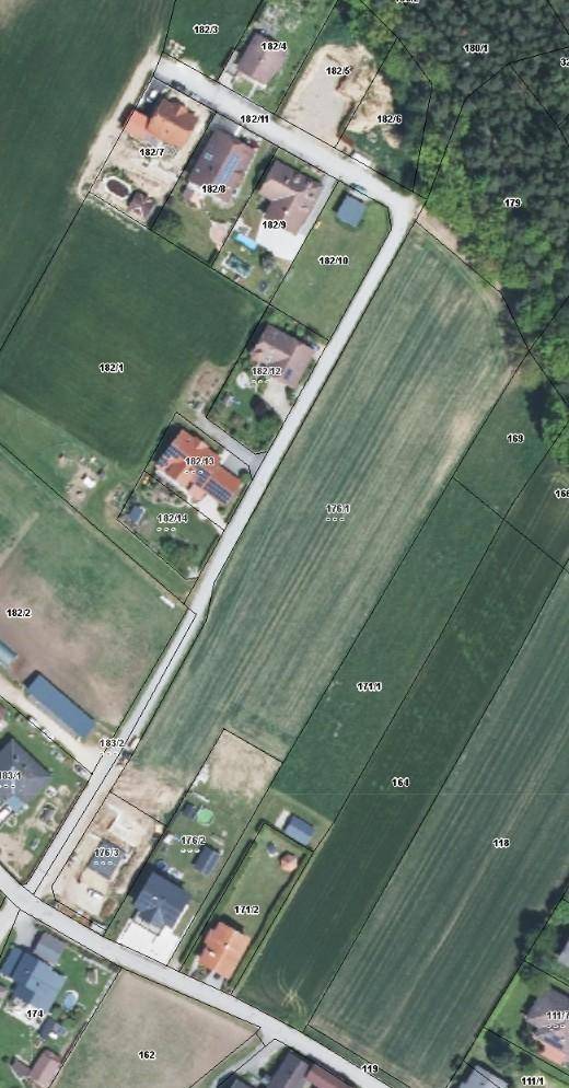 Luftaufnahme zeigt Wohnsiedlung mit Häusern, Feldern und Straßen in ländlicher Umgebung.