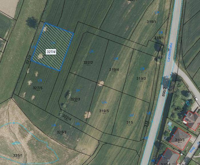 Luftaufnahme von landwirtschaftlichen Flächen und Parzellen mit angrenzender Straße und Bebauung.