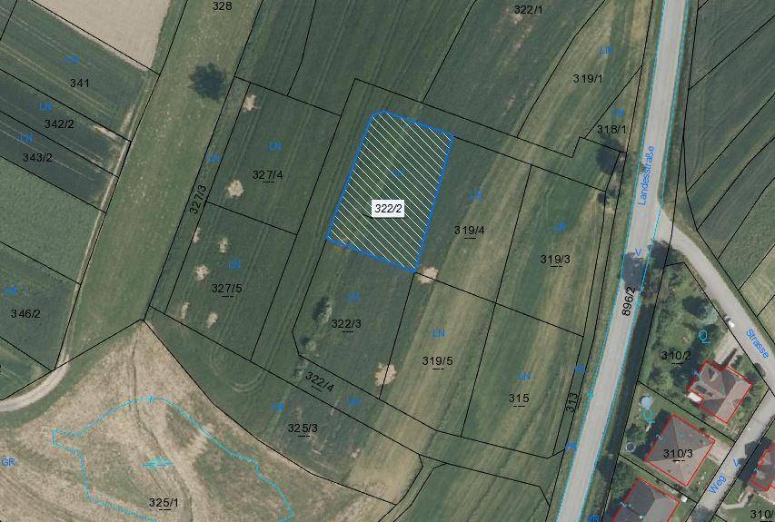 Luftaufnahme von landwirtschaftlichen Flächen mit einer markierten Parzelle und angrenzender Landstraße.