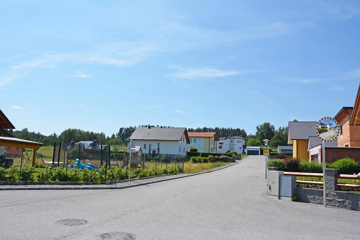 Ruhige Wohnstraße mit Einfamilienhäusern und einem kleinen Spielplatz in ländlicher Umgebung.