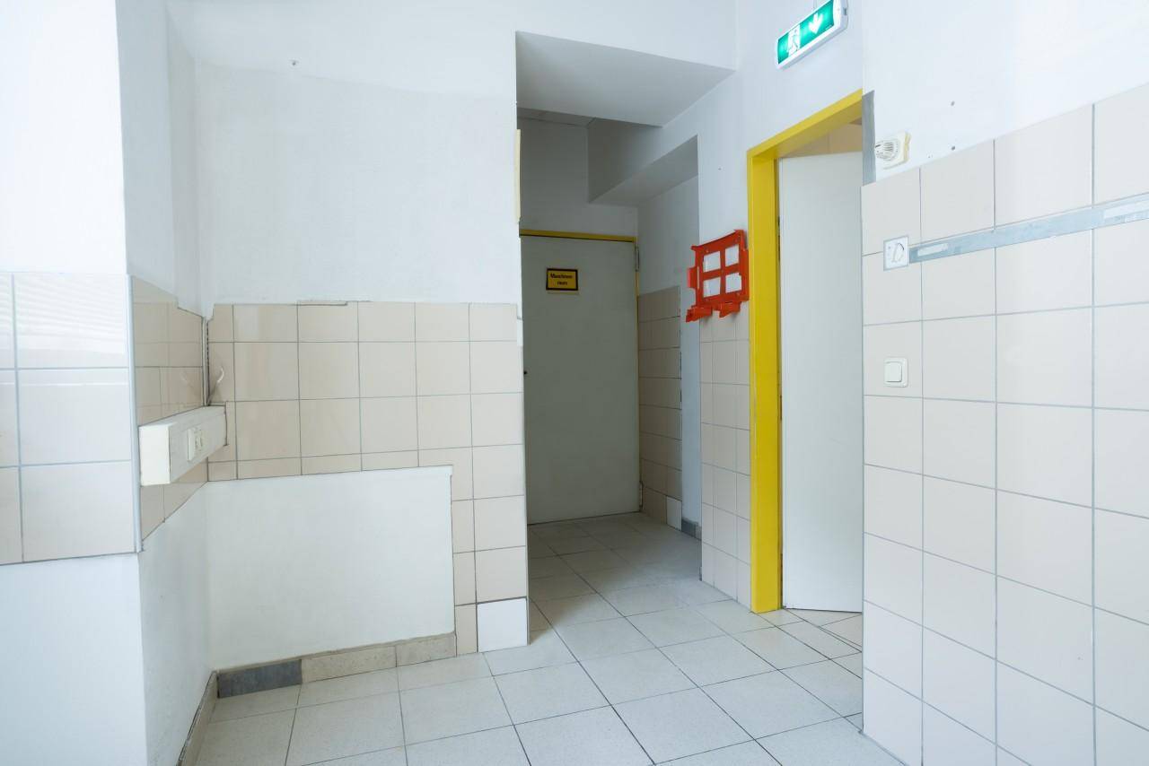 Heller Flur mit teilgefliesten Wänden und Ausgangsschildern.