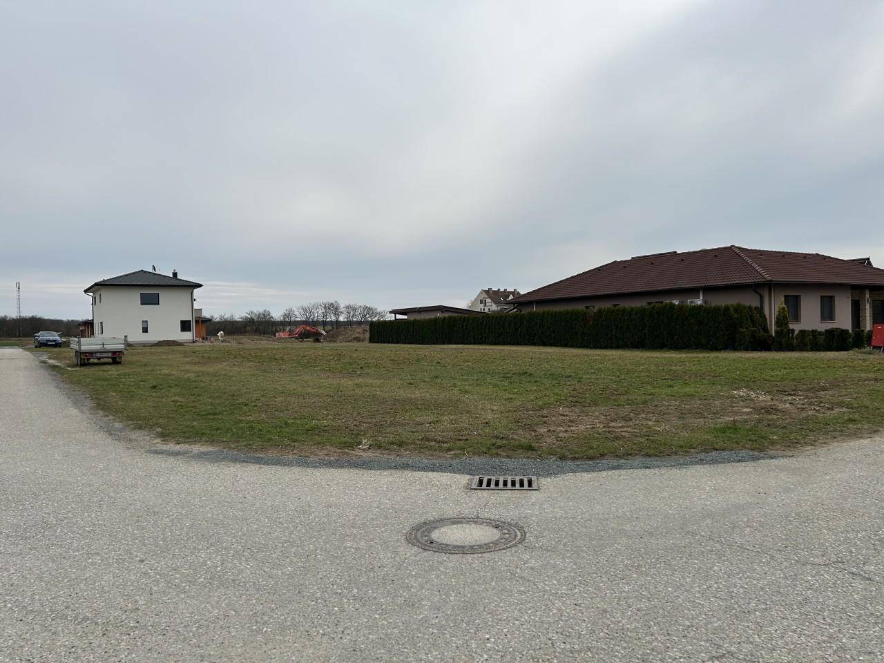 Weitläufiges Baugrundstück in einer ruhigen Wohngegend mit Blick auf moderne Neubauten und grüne Hecken.