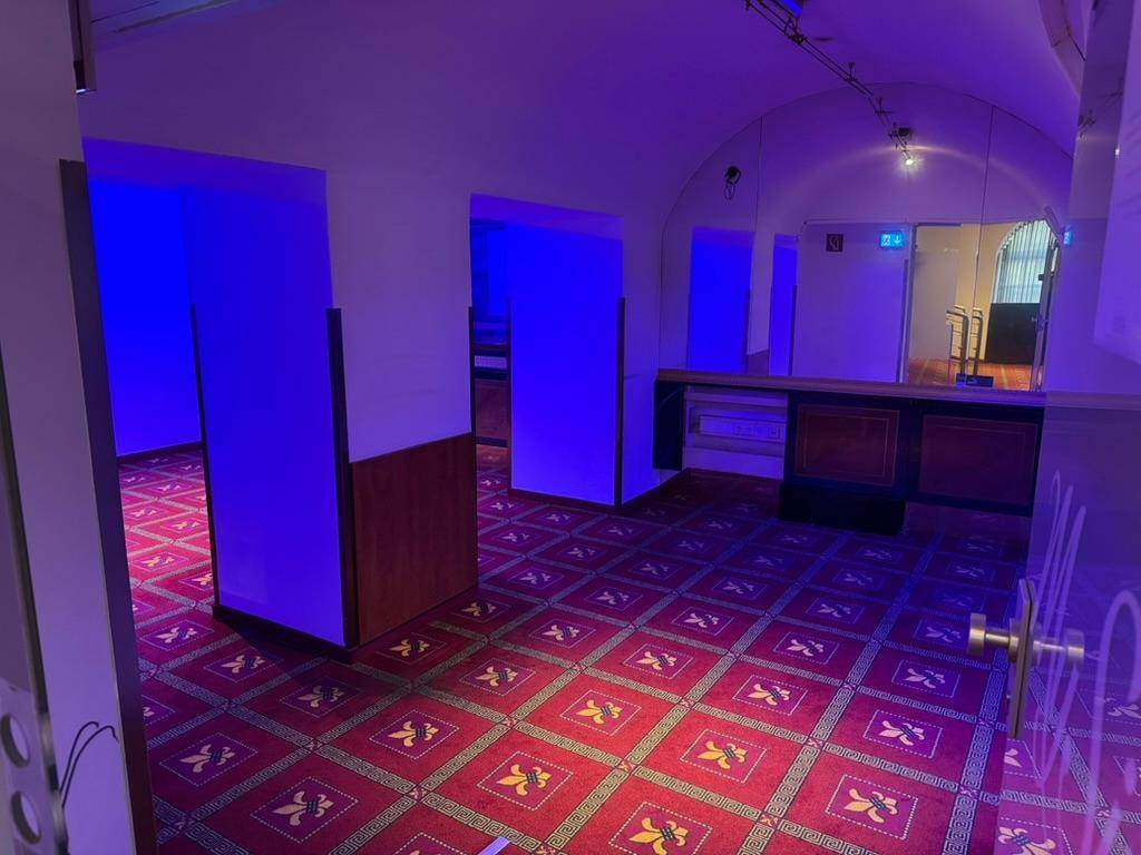 Großer Lounge-Bereich mit rotem Teppich, blauer Beleuchtung und gewölbter Decke.