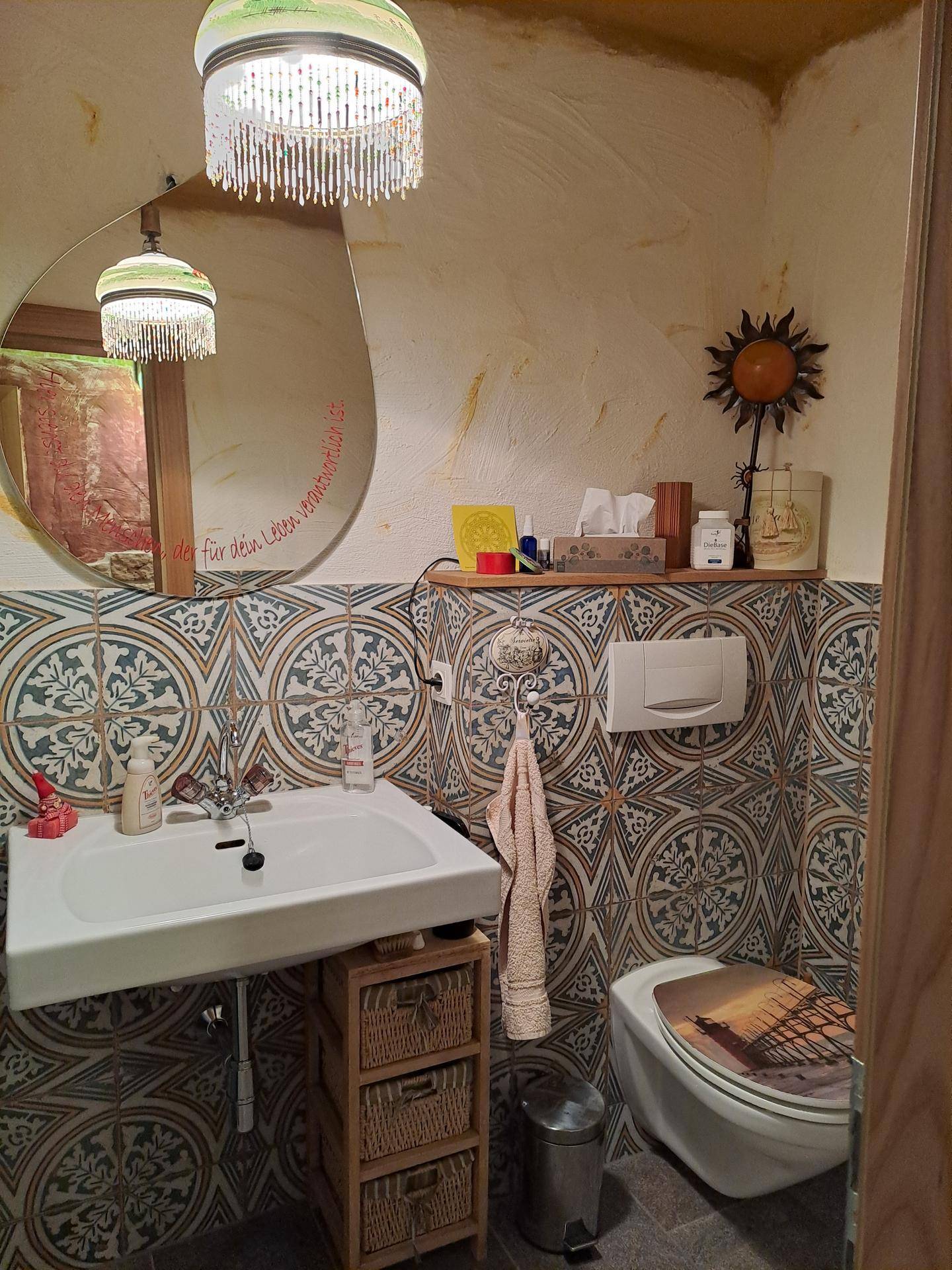 Badezimmer mit einem Waschbecken, einer wandhängenden Toilette und auffälligen gemusterten Fliesen an den Wänden.