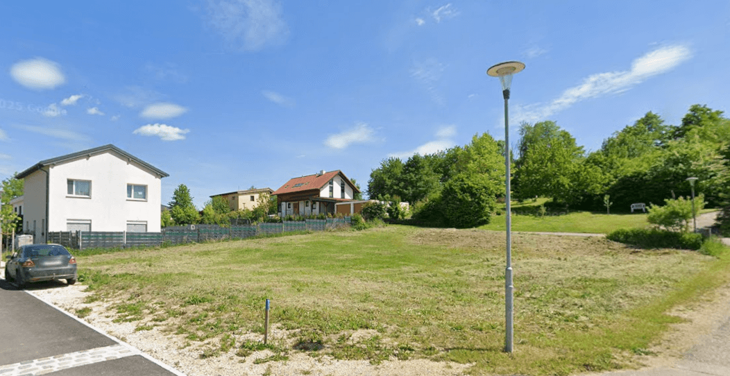 Weitläufiges Grundstück mit Grünfläche und Blick auf umliegende Wohnhäuser in ländlicher Umgebung.