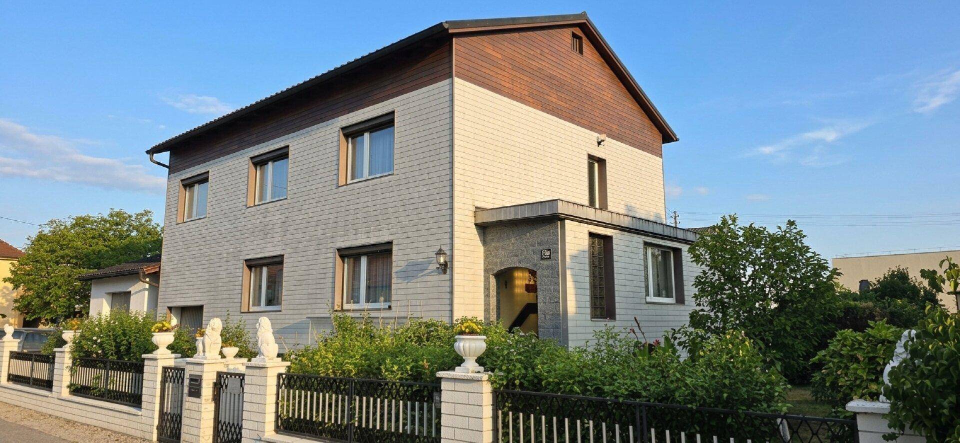 Zweistöckiges Wohnhaus mit heller Fassade und Holzakzenten unter einem Giebeldach.
